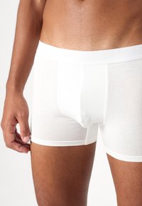 Weiße Baumwoll-Boxershorts mit enger Passform, ausgestattet mit einem weichen elastischen Bund und glatter Textur, die für Komfort und Unterstützung ausgelegt sind.