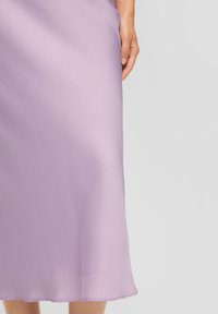 Lila midi rok van textiel met een vloeiende silhouet en een licht uitlopende zoom. Licht weerkaatst zacht van het materiaal.
