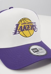 Lila-weiße Baseballmütze mit einem Los Angeles Lakers-Logo. Das Material besteht aus einer Baumwollmischung, hat einen gewölbten Schirm und einen verstellbaren Riemen.