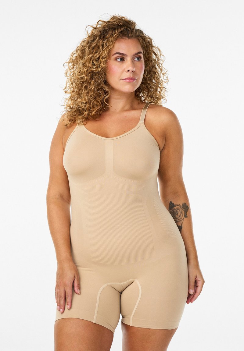 Beige shapewear bodysuit met verstelbare bandjes, met een geribbelde textuur en naadloos ontwerp, reikt tot halverwege de dijen.