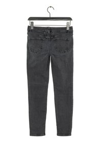 Jeans de mezclilla negra ajustados con una textura desgastada, diseño de cinco bolsillos y herrajes metálicos, colgados de una percha negra sobre un fondo blanco.