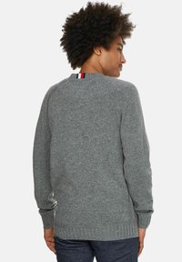 Grauer Strickpullover mit rundem Halsausschnitt, gerippten Bündchen und Saum. Verfügt über einen gestreiften Akzent am Nacken in Rot, Weiß und Blau.