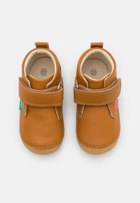 Chaussures pour bébé en cuir marron avec une sangle velcro. Bout rond et doublure intérieure douce. Étiquettes verte et rouge de chaque côté. Taille 20.