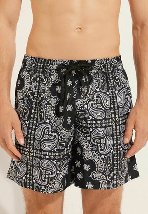 Czarne kąpielówki z wzorem w paisley w białym i żółtym kolorze. Posiadają elastyczny pas z sznurkiem i luźny krój.