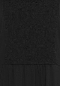 Robe noire avec un corsage froncé et une partie inférieure fluide, fabriquée en tissu doux avec une texture lisse et sans motifs visibles.