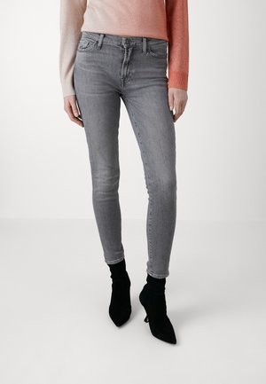 Jeans en denim gris fins avec une taille mi-haute, un design à cinq poches et un léger délavage. Assortis à des bottines noires à bout pointu.