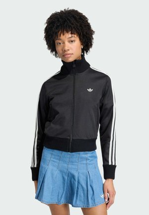 Zwarte sportieve jas met ritssluiting, hoge kraag, geribbelde boorden en zoom, met witte strepen langs de mouwen en een klein logo op de borst.