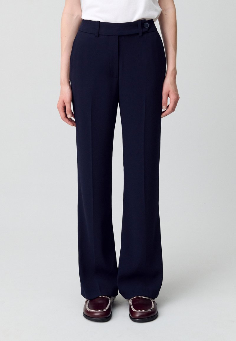 Pantalones anchos de marinero con una textura suave, que presentan un corte recto, pliegues delanteros y un detalle de botón en la cintura.