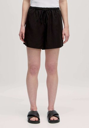 Zwarte lichte shorts van zachte stof, met een elastische tailleband en koord. Eenvoudig ontwerp, knielang, gladde textuur.