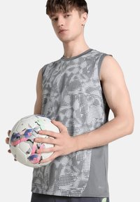 Maglietta sportiva grigia senza maniche con un design a motivo, abbinata a un pallone da calcio bianco con accenti multicolori.