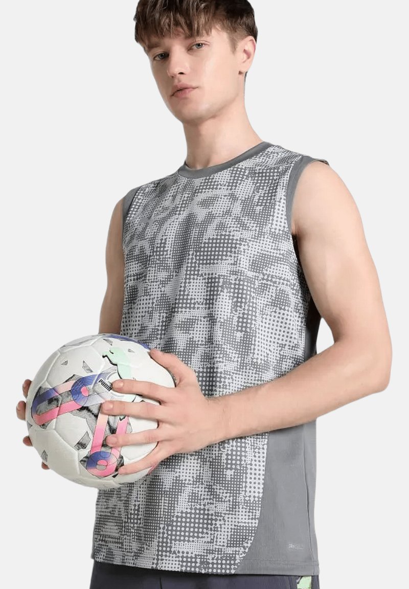 Maglietta sportiva grigia senza maniche con un design a motivo, abbinata a un pallone da calcio bianco con accenti multicolori.