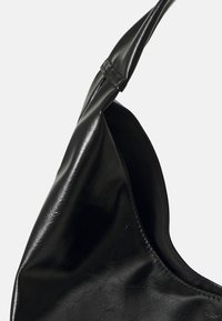 Černá taška z umělé kůže s hladkým povrchem, zaobleným tvarem a jedním širokým ramenním popruhem. Interiér je podšitý látkou.