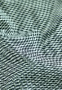 Patterned fabric featuring a grid-like design in shades of green and dark blue, showcasing a smooth, textile texture.