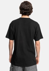 Zwarte katoenen t-shirt met korte mouwen, ronde hals en een ontspannen pasvorm. De textuur lijkt zacht en lichtgewicht. Geen zichtbare grafische afbeeldingen of patronen.