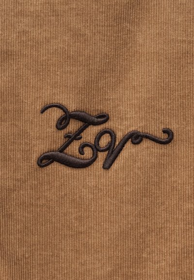 Καφέ υφαντό καστόρι με μαύρα κεντημένα στυλιζαρισμένα γράμματα «ZV» σε καλλιγραφικό στυλ.
