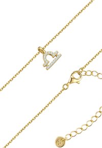 Kuldne käevõru, millel on kristallidega kaunistatud Kaalude sümbol ja homaariklamber koos väikese logo sildiga.