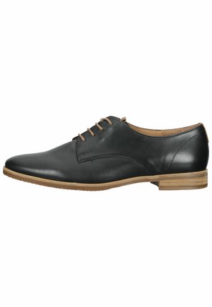 Chaussure en cuir noir avec une surface lisse, bout rond et détail de laçage. Présente une semelle marron clair avec un léger talon et des coutures subtiles.