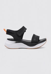 Sandalias de tela negra con correas ajustables, suela intermedia blanca y acento naranja. Presenta una plantilla texturizada y suela de goma para un mejor agarre.