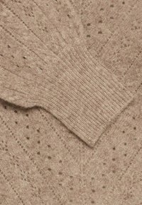 Maglione lavorato a maglia in beige chiaro, caratterizzato da un motivo testurizzato con punti ad intaglio e polsini a coste. Materiale morbido con una vestibilità rilassata.