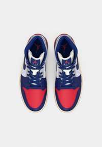 Scarpe da ginnastica alte con una combinazione di colori bianca, rossa e blu. Presentano una punta rossa perforata, lacci blu e un logo sulla linguetta. Suola in gomma.