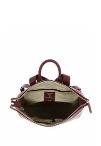Sac en cuir bordeaux avec deux poignées, fermeture éclair et intérieur beige. Présente une étiquette indiquant "DESIGNÉ EN ALLEMAGNE." Montre des poches intérieures.