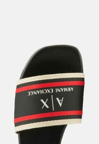 Infradito neri con una larga fascia a righe caratterizzata da dettagli bianchi e rossi. La fascia mostra la scritta "ARMANI EXCHANGE" in bianco.