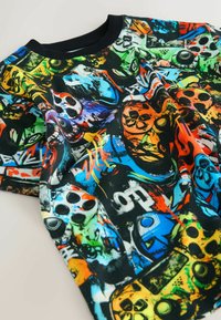 Cămașă cu mânecă scurtă din bumbac, având un print grafic multicolor cu controlere de jocuri și modele pe un fond negru.