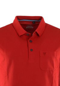 Rød polo t-shirt med klassisk krave, tre sorte knapper, en brystlomme og tekstureret stof med en lille logo detalje.