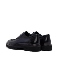 Donkerblauwe leren schoenen met een gladde afwerking, ronde neus en dikke zwarte rubberen zolen. Beschikt over vijf veterogen en accentstiksels.