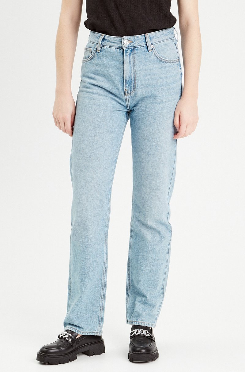 Light blue denim jeans with a high waist, straight leg, five-pocket design, and contrast stitching. Paired with black platform shoes.