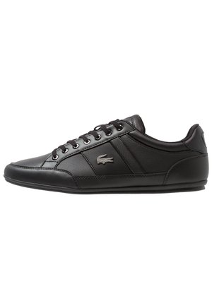 Czarny niski skórzany sneaker z sznurowaniem z przodu i małym logo krokodyla po boku.