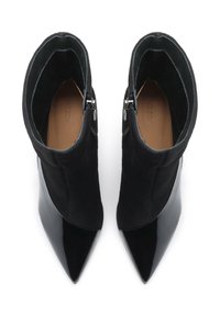 Botines negros con puntera afilada y una combinación de cuero patentado liso y suave ante. Cierre lateral con cremallera para un acceso fácil.