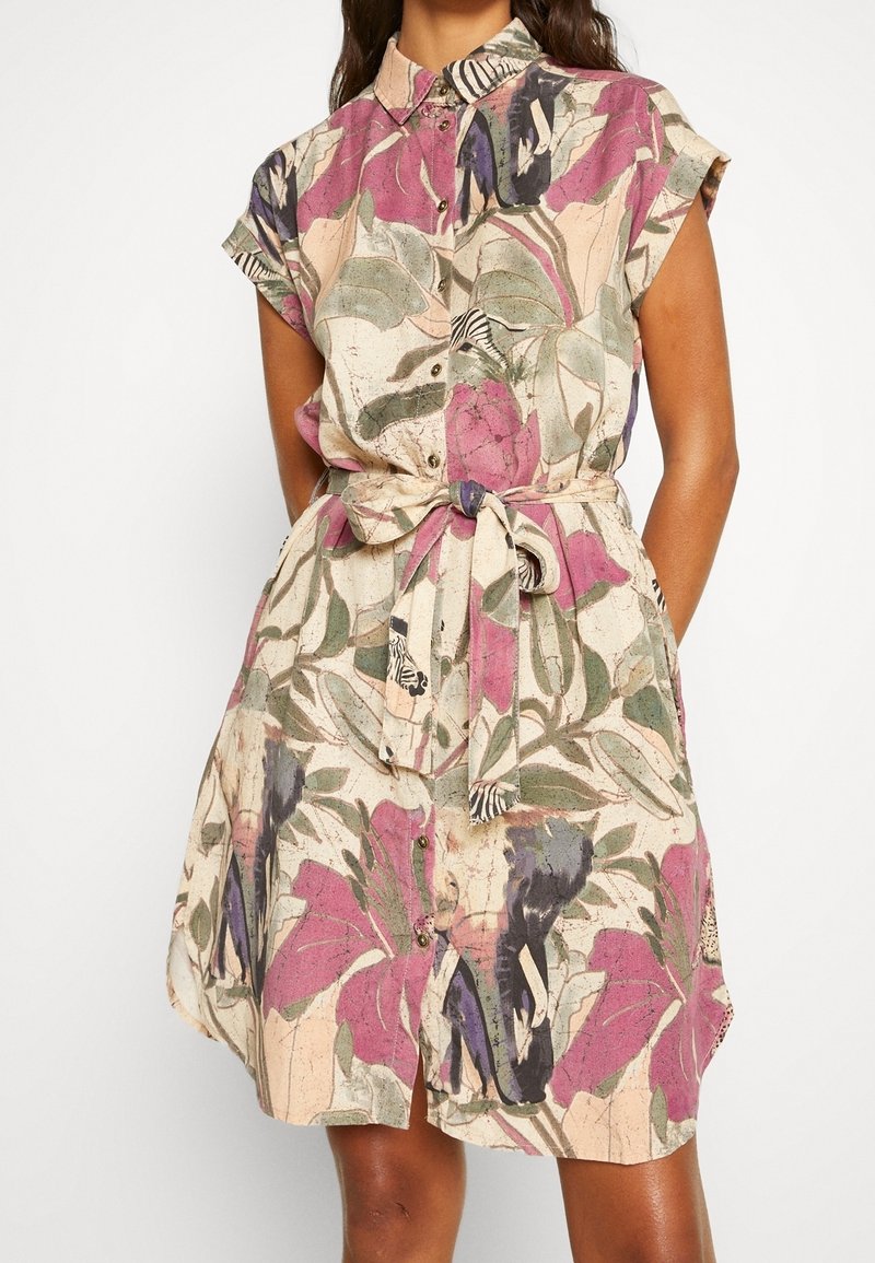 Robe chemise à manches courtes en tissu léger, présentant un motif floral en violet, vert et rose, avec une ceinture et un devant à boutons.