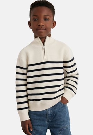 Pull crème avec col zippé mi-haut, comportant des rayures horizontales bleu marine et un tissu texturé. Coupe ample avec des poignets et un ourlet côtelés.