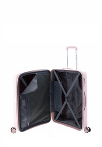 Valigia rigida di colore rosa chiaro con manico retraibile, scomparti con zip e cinghie elastiche incrociate all'interno; ruote lisce per il trascinamento.