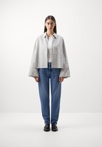 Stripete, lettvekts, kort jakke med knappelukking, kombinert med høyvekts blå jeans. Begge har avslappet, løst passform.