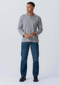 Grå langærmet polo t-shirt med krave, letvægtsstof, parret med mørkeblå jeans og sorte snøre-sko. Enkel design, afslappet pasform.