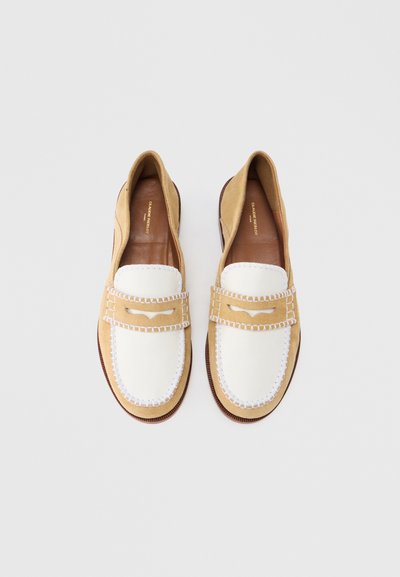 Τακούνια μοκασίνια από καφέ σουέντ με λευκό δέρμα στο μπροστινό μέρος, διακοσμημένα με λευκή ραφή. Επίπεδο τακούνι και στρογγυλεμένη μύτη. Επενδυμένα με καφέ δέρμα.