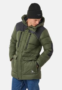 Green puffer jacket with a black patterned upper, zippered pockets, and a hood. Accompanied by a black knit beanie.