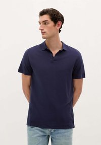 Kortærmet navy polo t-shirt i blødt bomuldsstof, med krave og en afslappet pasform. Diskrete sideslids ved kanten for nem bevægelse.