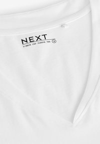 Vit V-krage t-shirt med kapslängd ärm i mjukt tyg, med en etikett som har "NEXT"-logotyp och storleksangivelse. Slät yta med rena sömmar.