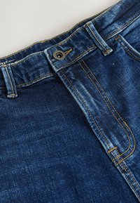 Blugi din denim albastru închis, cu un fermoar și o închidere cu buton vizibile, având cusături portocalii contrastante și o textură netedă.