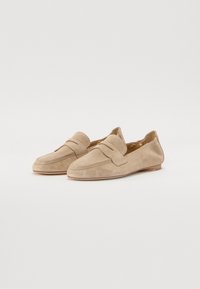 Beige semskede loafers med rund tå, med sømdetaljer og lav hæl. Har en rem over overdelen for ekstra design.
