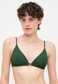 Haut de bikini vert avec une texture côtelée, présentant un design triangulaire et des bretelles fines et ajustables. Comprend un détail à double sangle à la base.