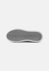 Shoe sole with a textured gray rubber surface. Rounded shape, white edge, and a honeycomb pattern for enhanced grip.