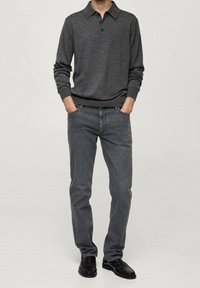 Dunkelgrauer Poloshirt mit Kragen und drei Knöpfen, kombiniert mit grauen Jeans und schwarzen Schuhen. Glatte Textur, taillierte Passform.
