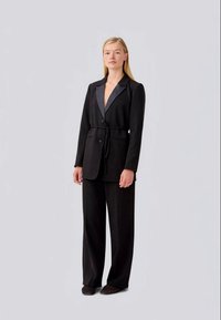 Black blazer with a satin lapel, two buttons, and a tied waist, paired with wide-leg trousers. Smooth texture and tailored fit.