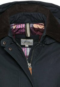 Marineblauwe jas met ritssluiting, corduroy kraag en gestreepte binnenvoering in paarse, roze en crèmekleurige tinten. Merklabel zichtbaar.