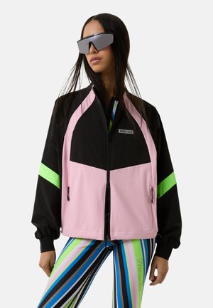 Black and pink color-blocked jacket with neon green accents; features a zippered front and elastic cuffs; paired with striped leggings.