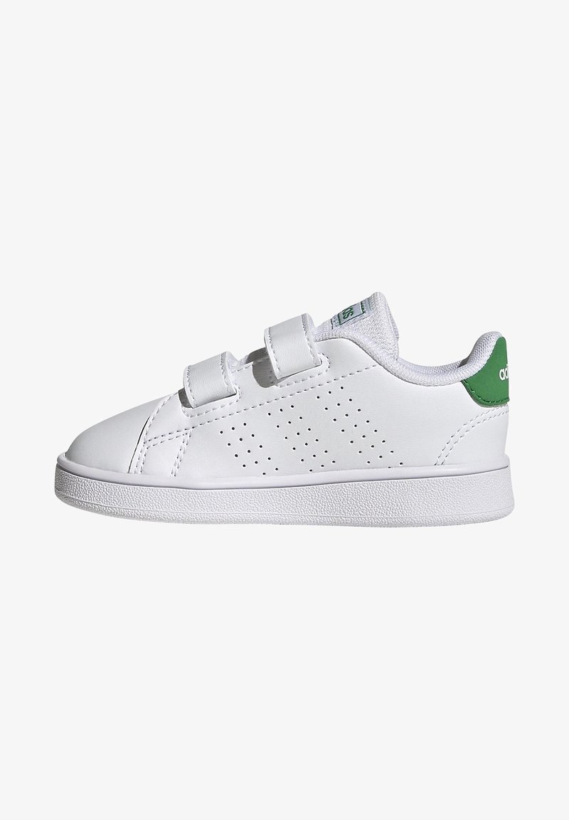 White sneakers with a smooth leather exterior, adjustable Velcro straps, perforated side design, and green heel accent. Textured rubber sole.